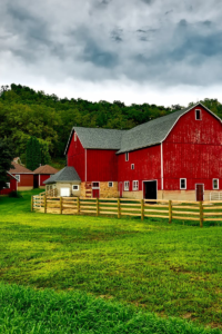 Vibrant red barn amidst lush greenery and cloudy skies in Wisconsin.